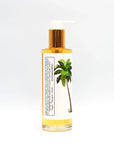 Side view of a clear bottle with gold pump, palm tree label, containing body oil