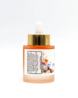 Orange glass face oil bottle with gold dropper cap and floral label on white background